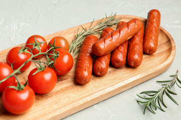 Wooden board with tasty grilled sausages and fresh tomatoes on light background, closeup