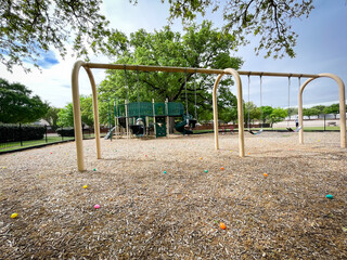 Huge swings with colorful plastic eggs on mulch ground for kids Easter egg hunt activity at large playground with oak trees near Dallas, Texas, USA