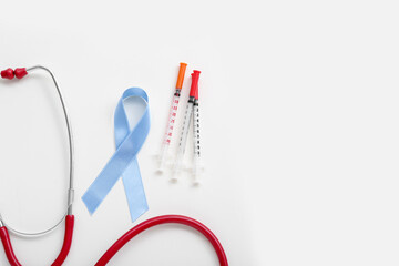 Awareness ribbon with syringes and stethoscope on white background. Diabetes concept