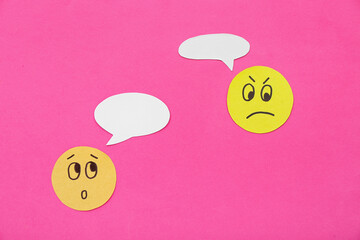 Paper faces with speech bubbles on pink background. Dialogue concept