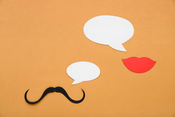 Paper mustache and lips with speech bubbles on orange background. Dialogue concept