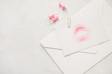 Envelope with lipstick kiss mark and paper clips on white background