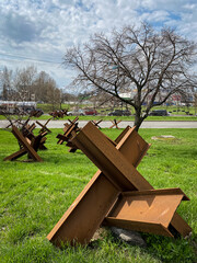 War in Ukraine. Early spring. The peach trees are in bloom. Anti-tank hedgehogs at the entrance to...