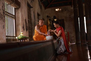 Asia woman with red Thai traditional dress respect Monk on Songkran festival in Chapel, Thai culture on holy day