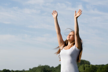 woman standing with arms raised, saluting the sun outdoors