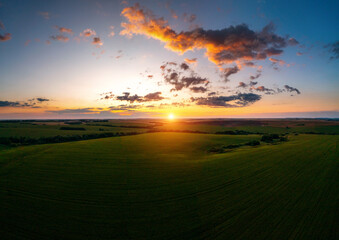 Naklejka na ściany i meble Breathtaking sunset over farmland in summer taken from a drone.