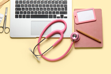 Stethoscope, laptop and notebook on yellow background