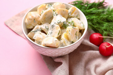 Bowl of tasty Potato Salad with greens on pink background, closeup