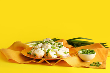 Plate of tasty Potato Salad with greens on yellow background