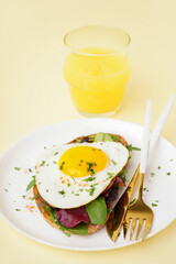 Delicious sandwich with fried egg and greens on beige background