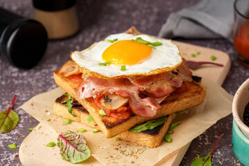 Delicious sandwich with fried egg and bacon on grey background