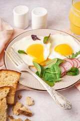 Plate with tasty fried egg, radish and spinach on light background