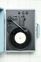 Record player with vinyl disk on white tile background