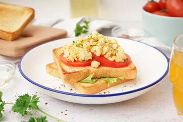 Plate with tasty scrambled eggs sandwich on table