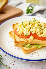 Plate with tasty scrambled eggs sandwich on table