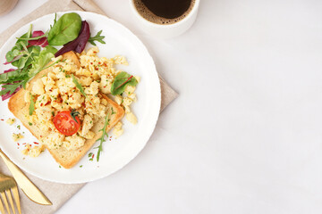 Plate with tasty scrambled eggs sandwich and salad on light background