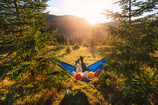 Family holiday on tourist trip. Children lie in tourist hammock in the forest on mountain landscape background. Top view, wide angle shooting.
