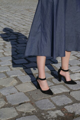 Woman in midi blue dress and pointed toe pumps with block high heels and ankle strap on the cobblestone street