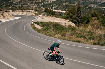 Woman cyclist riding a gravel bike with a view of the spanish mountains.Fit athlete wearing...