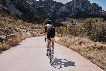 Man cyclist on a gravel bike riding on the road in the hills with a view of the mountains.Man cyclist wearing cycling kit and helmet