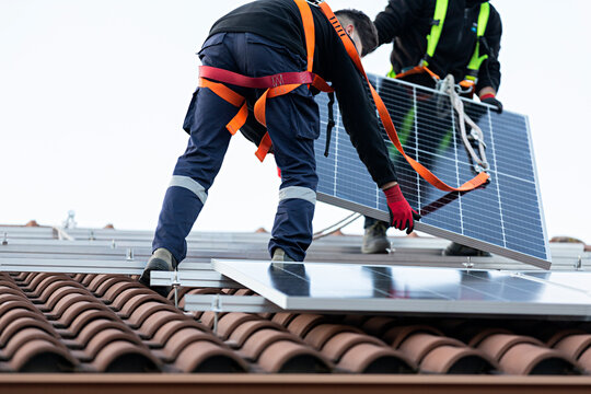 Pareja de t&eacute;cnicos instalando placas solares en una vivienda. 10	