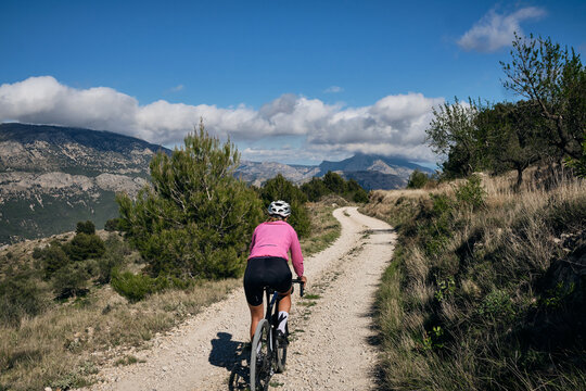 Spanish gravel adventures.Female cyclist riding a gravel bike on a gravel road with a view of the mountains.Beautiful sunny day for cycling.Beautiful motivation image of an athlete.Spain.