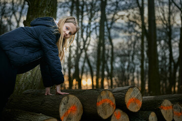 Fototapeta premium A girl plays on logs of fallen trees.