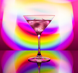 Alcoholic cocktail in a glass goblet against the background of colorful neon lights