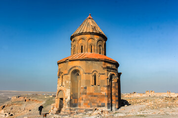 Experience the ancient wonders of Ani Ruins in Kars, Turkey with this stunning photo of an intricate stone church against a mountainous backdrop. Discover history and culture in this scenic landmark.