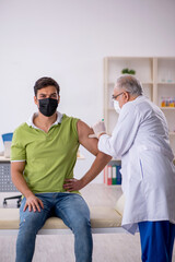 Fototapeta premium Young male patient visiting old male doctor in vaccination conce