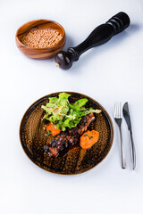 Marbled beef rib in spicy sauce with carrot puree and salad in a plate.