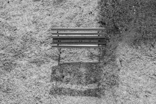 Black and white photo of single, old wooden chair on grass from top view