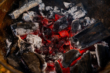 Red hot coals burning in high temperature and turning to white ash close up in metal mangal grill