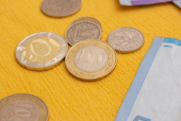 Coin 200 tenge. Kazakh money on yellow textile background. Cash of Republic of Kazakhstan. Concept of currency exchange, moving, immigration, salary, debt, credit, travel, numesmatics, collectibles