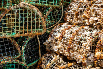 Stack of used and washed portable lobster traps, made with metal frames and plastic netting, are arranged side by side, creating an abstract scene that highlights the contrast between clean and dirty.