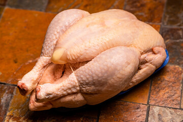 Fototapeta premium Whole whole chicken carcass on stone tile background.