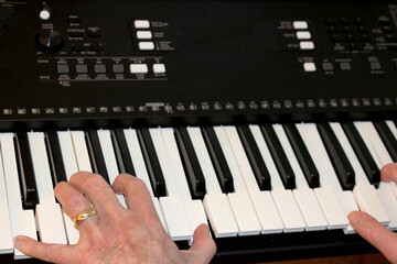 elderly white female hands making music while pressing keys while playing electric piano