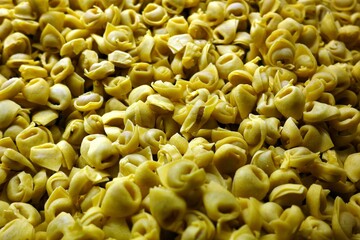 Background Italian uncooked pasta Tortellini with cheese. Traditional Italian food.