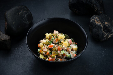 Fresh salad Olivier from boiled potatoes, carrots, green peas, cucumbers, eggs, chicken ham and mayonnaise.