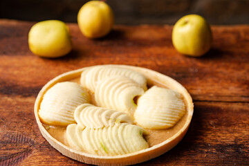 Frozen apple pie. Apples in caramel sauce in foil shape on wooden background.