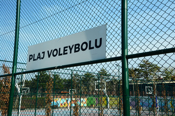 Beach volleyball field sign in Turkish on a fence in a sunny day.