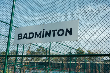 Badminton field sign on a fence in a sunny day.