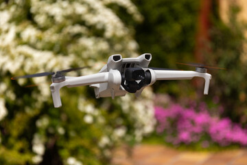 Front view of a small drone with blured flowers in the background