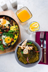 Eggs with bacon, onion, mushrooms, zucchini, herbs and green snack with bread and glass of juice.