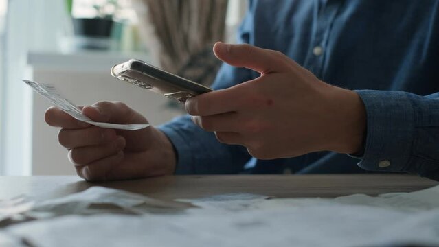 Man pays bills from smartphone scanning qr code of receipts