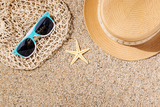 Straw hat and sunglasses on the beach sand