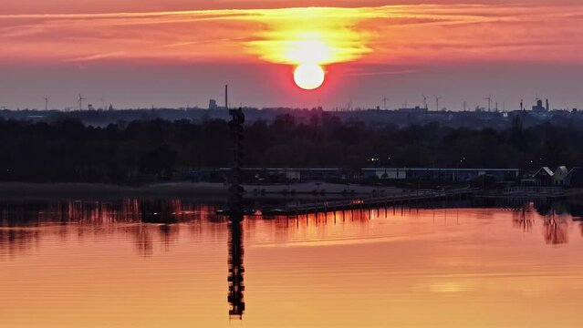 sunset at the Goitzsche near Bitterfeld. the sky and the water are colored red by the setting sun. Wind turbines can be seen in the background.