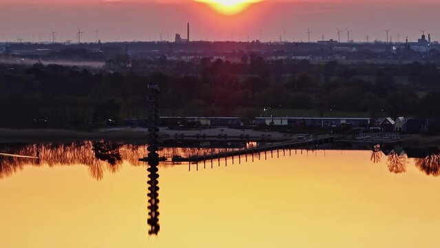 Gro&szlig;er Goitzsche See near Bitterfeld at sunset. red colored sky and yellow water surface. electric wakeboard rides on the water. reflections on the water.