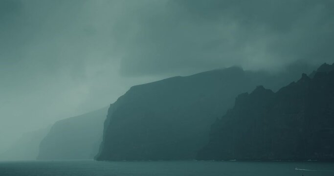 Gloomy ocean landscape with gray storm clouds. Fog covered high sea cliffs on shore. Mystical foggy haze inspires fear and greatness.