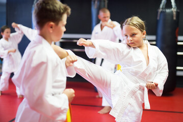 Fototapeta na wymiar Preteen children practicing new karate moves in pairs at sport gym